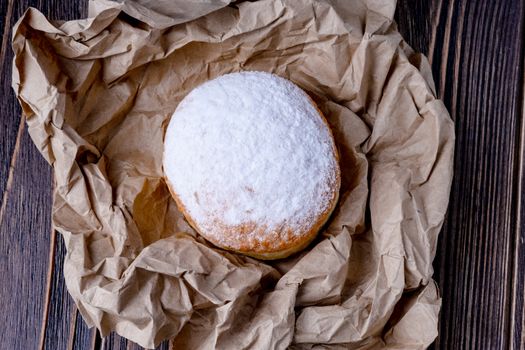 Berliner jelly filled doughnut with raspberry and redcurrant on wooden background.