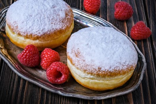 Berliner jelly filled doughnut with raspberry and redcurrant on wooden background.