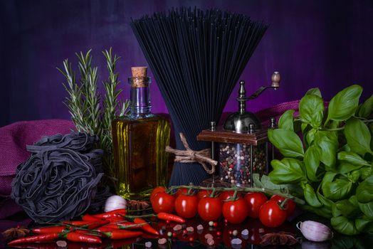 Various pasta and with herbs, spices condiments on black purple background. Cooking concept.