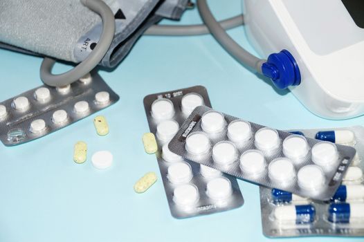 tonometer and pills on blue background, view from above.