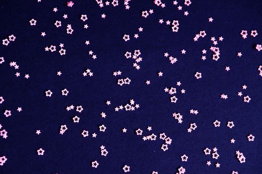 pink glittering stars on dark blue background close up