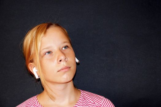 teenage girl listening to music on headphones , portrait on black background.