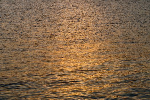 the setting sun is reflected in the dark sea water.
