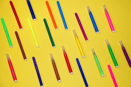 multicolored markers on a yellow background