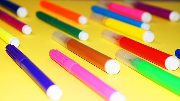 multicolored markers on a yellow background