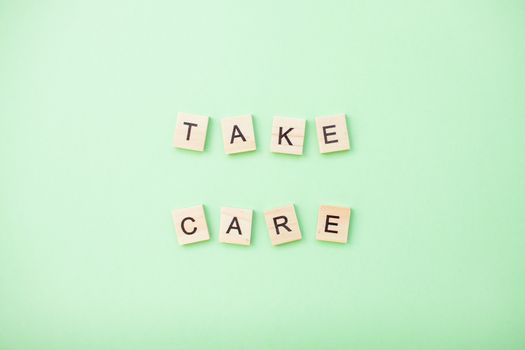 inscription from wooden blocks take care on a light green background