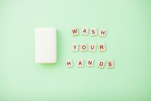 inscription from wooden blocks wash your hands and soap on a light green background