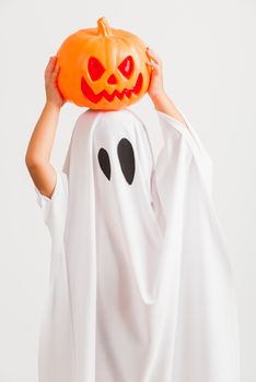 Funny Halloween Kid Concept, little cute child with white dressed costume halloween ghost scary he holding orange pumpkin ghost on hand, studio shot isolated on white background