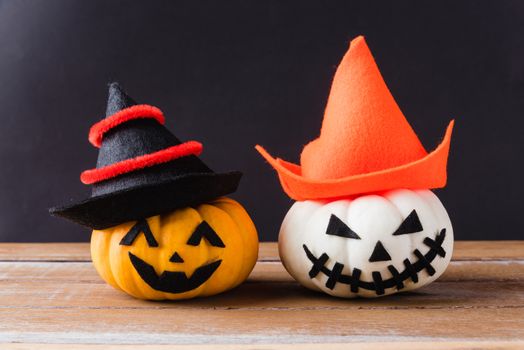 Funny Halloween day party concept ghost pumpkins head jack lantern scary smile wear hat on wooden table and black background, studio shot isolated, Holiday decoration