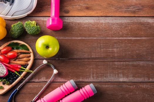 Top view of fresh organic fruit and vegetable in heart plate, shoes, sports equipment and doctor stethoscope, studio shot on wooden gym table, Healthy diet vegetarian food concept, World food day