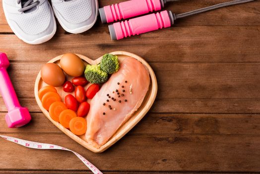 Top view of Raw chicken breasts fillets no boneless with spices in heart plate wood and sport or athlete's equipment dumbbell
running shoes on wooden background, Healthy lifestyle diet food concept