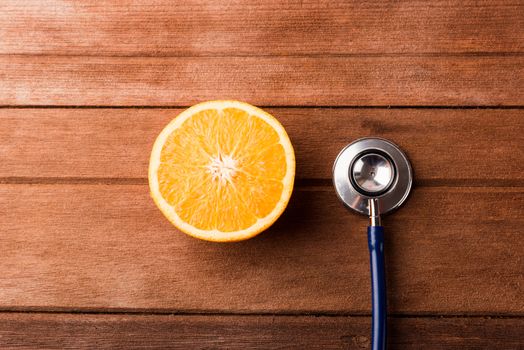 Orange fruit and Doctor stethoscope on wooden table, Vitamin C, Healthy lifestyle diet food concept