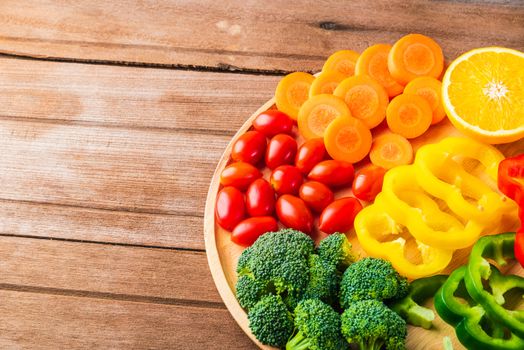 Top view of fresh organic fruits and vegetables in plate wood (carrot, Broccoli, tomato, orange, Bell pepper) on wooden table, Healthy lifestyle diet food concept