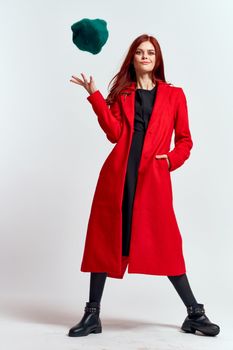 emotional woman in a red coat and with a hat in full growth on a light background black boots pose model. High quality photo