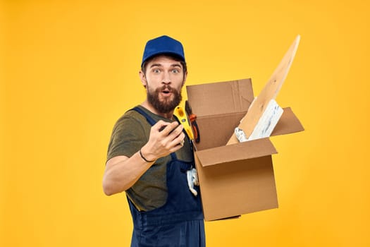 A man in a working form a box with loading tools yellow background. High quality photo