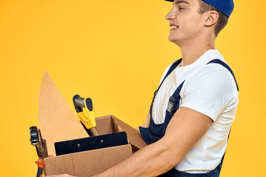 worker with box in hand tools loader yellow background. High quality photo