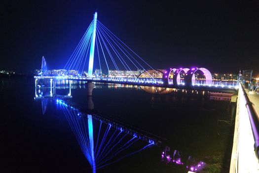 Night view of a beautiful scene of bridge over sea water in the evening time with colorful lights.