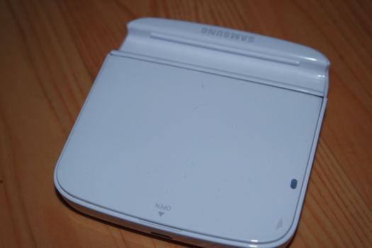 White colored battery charging box for electronic devices like mobile phone. Potable charging box is placed on a wooden floor.