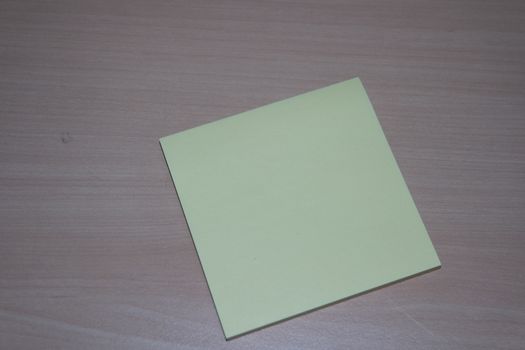 Close-up, selective focus: Yellow sticky note paper placed on a wooden table with copy space for text