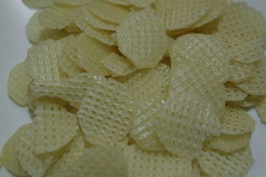 Closeup view with selective focus on dried chips as fast food for tea break. Potato chips with spices sprinkled on it. Fast food background for advertisements.