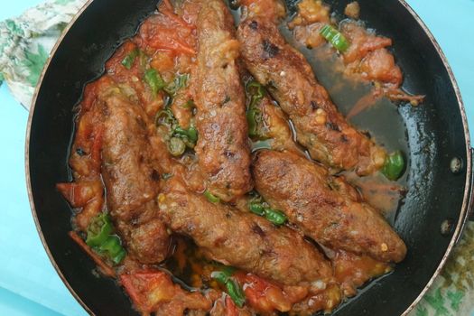 Closeup view of delicious spicy home made fried kebab with green mint leaves and green pepper sprinkled on it