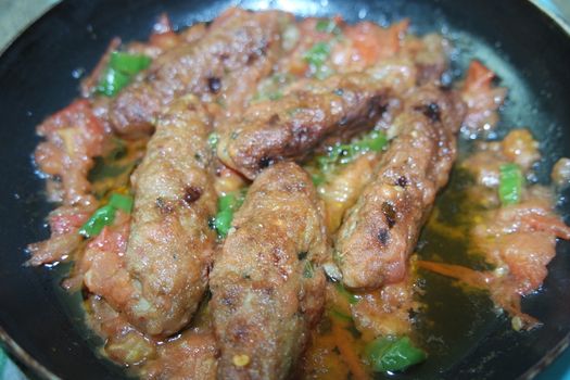 Closeup view of delicious spicy home made fried kebab with green mint leaves and green pepper sprinkled on it
