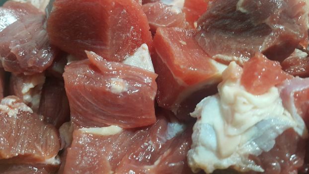Close up view of fresh finely chopped meat cubes. Red meat small steaks with whitish meat fat.