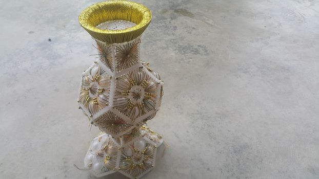 A beautiful ceramic vase placed on a grey floor. The ceramic vase has lovely designs and is used for flowers or bouquet