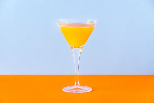 Fresh orange juice in glass on orange surface and light blue background