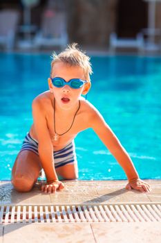 Cute happy little boy in goggles swimming and snorking in the swimming pool