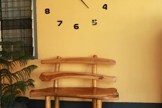 wooden bench near yellow wall. Vintage wooden bench under the wall clock.