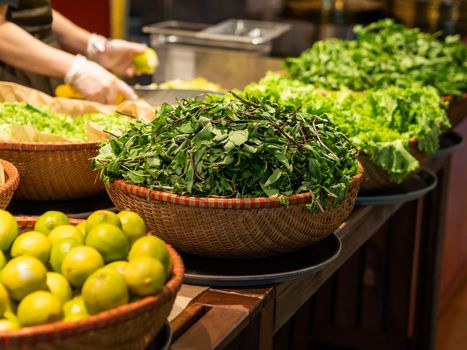 Chef cooks something tasty in Vietnamese restaurant. Wicker baskets with herbs for Asian cuisine. Mint, lime, pepper, lettuce.