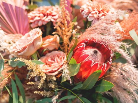 Close up photo of bouquet with Protea and roses. Red sugarbushes flower with leaves. Florist store, flower shop.