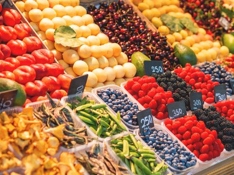 Fruit stand in the market. Sale of fresh exotic and local fruits and berries - raspberries, blackberries, peaches, apricots, avocados.