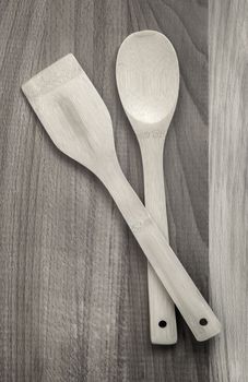 On a wooden table, kitchen utensils: a wooden spatula and a spoon. The view from the top, flat position, copy space