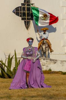 A gorgeous Hispanic Brunette model poses with traditional skull sugar makeup paint for a Mexican festival.