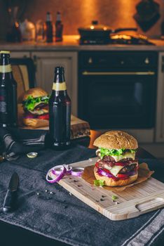 Dinner with Two Patties Cheeseburger and Couple Bottle of Beer on Kitchen Table.