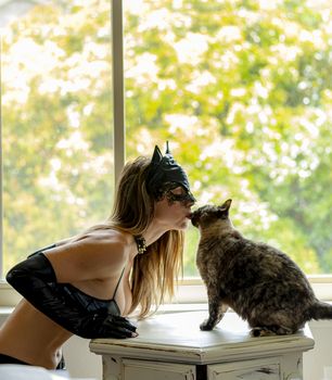 A gorgeous brunette model poses in a cat suit with her animal in a home environment