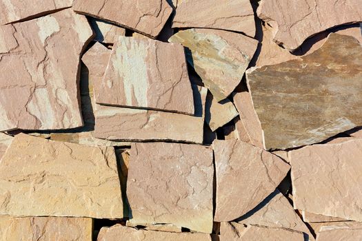 Texture and background of large slabs of brown sandstone in harsh sunlight.