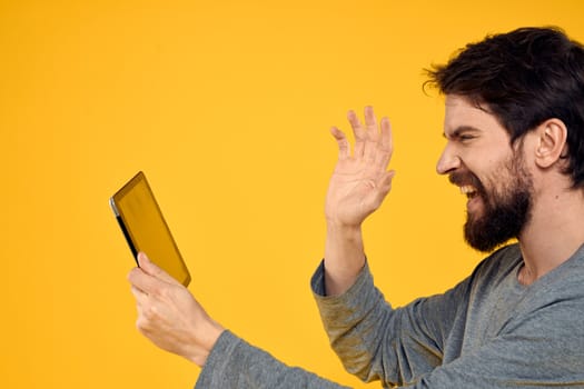 Bearded man with tablet in hands technology work wireless device yellow background. High quality photo