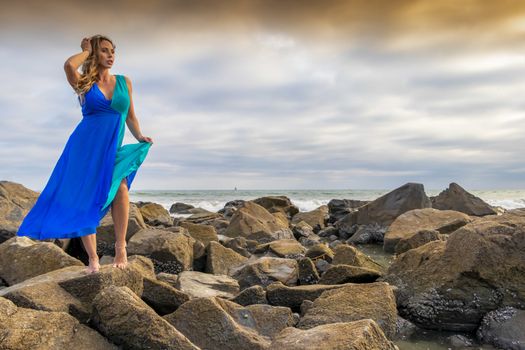 A beautiful brunette hispanic model posing outdoors on a beach at sunset