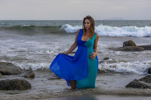 A beautiful brunette hispanic model posing outdoors on a beach at sunset