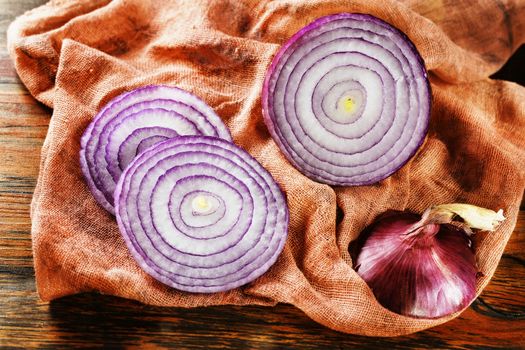 Slices of red onion  on wooden table lay on orange  cloth 