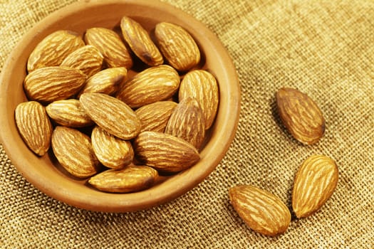 Beautiful shelled almonds in bowl on sackcloth background 