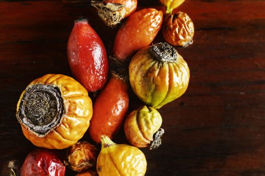 Several red and yellow rose hips on wooden table , beautiful saturated colors