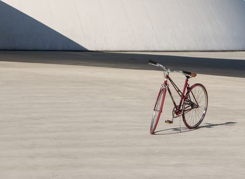 Red bike alone in concrete park. Copy space.