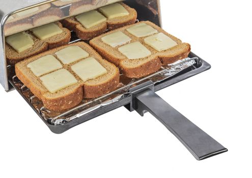 Horizontal shot of four pieces of buttered wheat bread about to be pushed into the toaster and toasted.