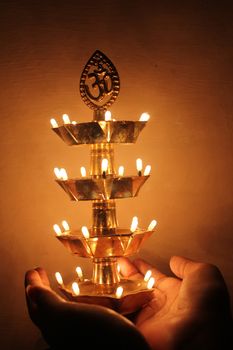 Hand holding beautiful traditional indian lamp illuminated in dark