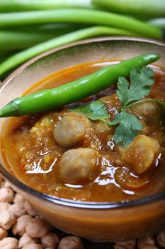 spicy chana masala, raw chickpeas around the bowl with green chilli topping, indian dish