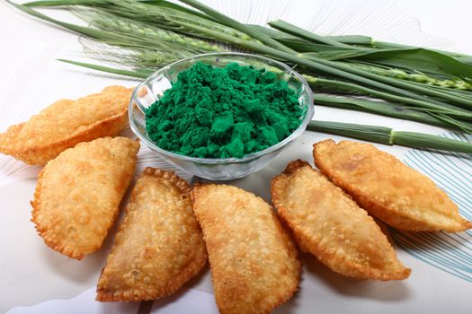 gujia, indian traditional snacks for holi festival with green color in bowl